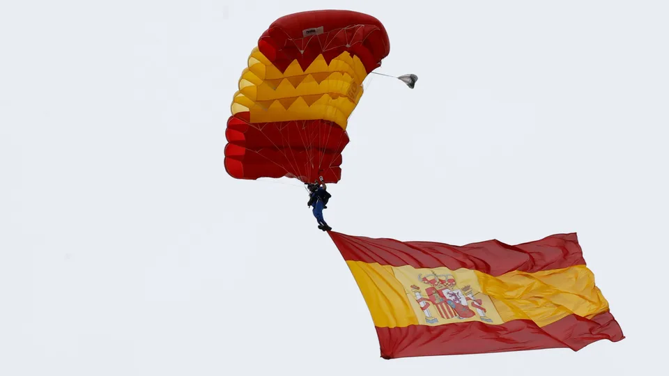 Bandera de España ondeando bajo un cielo nublado, fotografía de archivo.