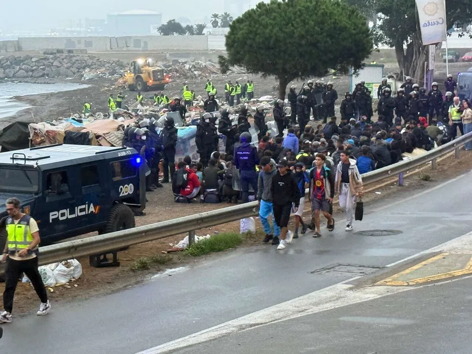 Agentes de la Policía Nacional, vehículos policiales y grupos de personas junto a una zona costera.