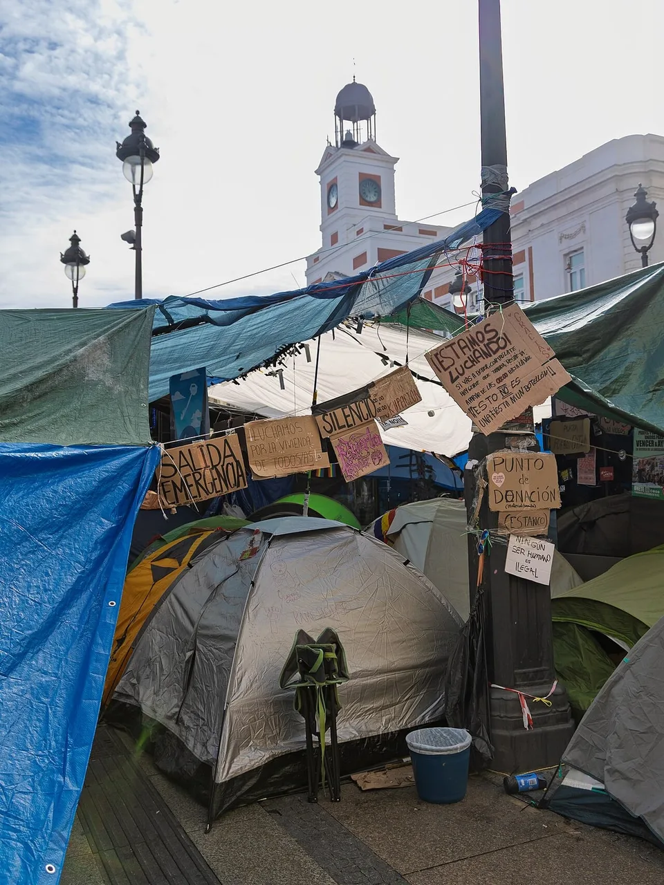 Acceso a la acampada por la vivienda en la Puerta del Sol junto a la calle Arenal, fotografiado la mañana del 5 de octubre de 2026, con tiendas, lonas y carteles.