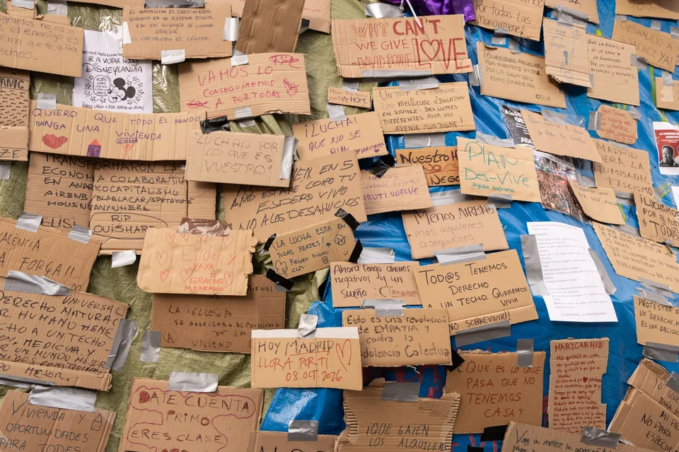 Carteles reivindicativos escritos a mano sobre una lona azul de la acampada por la vivienda en la Puerta del Sol de Madrid el 11 de octubre de 2026.