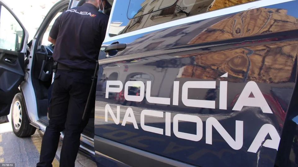 Agente de Policía Nacional junto a un vehículo oficial en una fotografía de apoyo institucional difundida con la noticia de Abastos.
