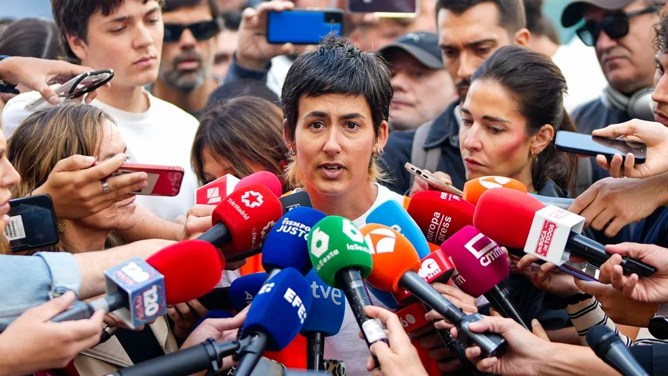 Una mujer comparece ante numerosos micrófonos y periodistas en el exterior.