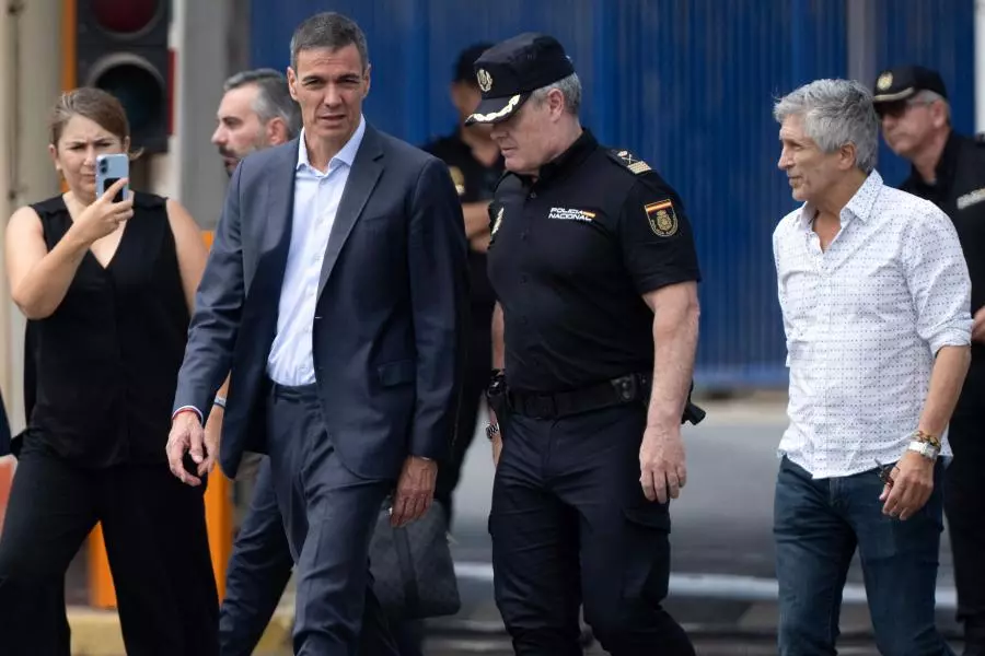 Responsables institucionales y un agente uniformado de la Policía Nacional caminando junto a un edificio de acceso controlado.